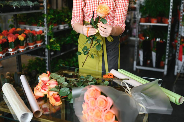 happy girl gardener in the flower shop make bouquets for a holiday. Lifestyle flower shop - Fotografie, Obrázek