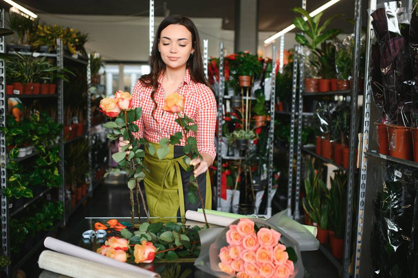 Young beautiful woman florist make bouquet of flowers at flower shop. - Foto, imagen