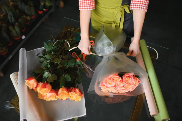 happy girl gardener in the flower shop make bouquets for a holiday. Lifestyle flower shop - Photo, image