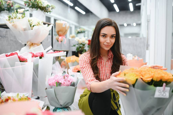 Beautiful young florist in flower shop. - Fotografie, Obrázek