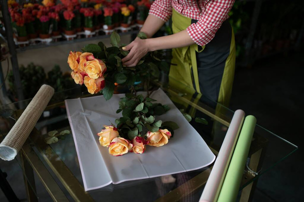 Young beautiful woman florist make bouquet of flowers at flower shop. - Zdjęcie, obraz