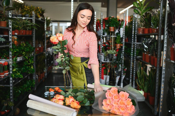 gelukkig meisje tuinier in de bloemenwinkel maken boeketten voor een vakantie. Lifestyle bloemenwinkel - Foto, afbeelding