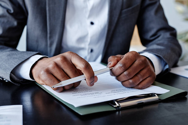 Blisko udanego African American wykonawczej trzymając długopis w ręku podczas notatek na spotkaniu biznesowym - Zdjęcie, obraz