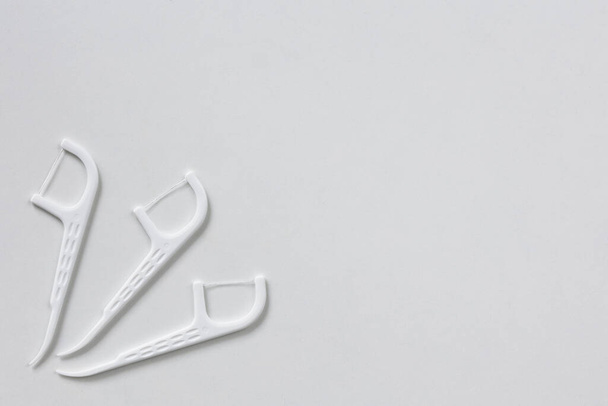 白い背景にデンタルフロスのある3つのプラスチック製の白い歯科用爪楊枝 - 写真・画像