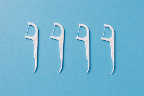 Set of white dental toothpicks with dental floss on blue background - Foto, Imagen