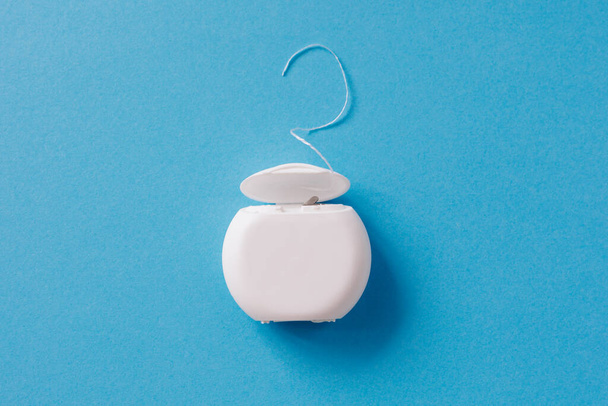 Dental floss for cleaning teeth on blue background - 写真・画像
