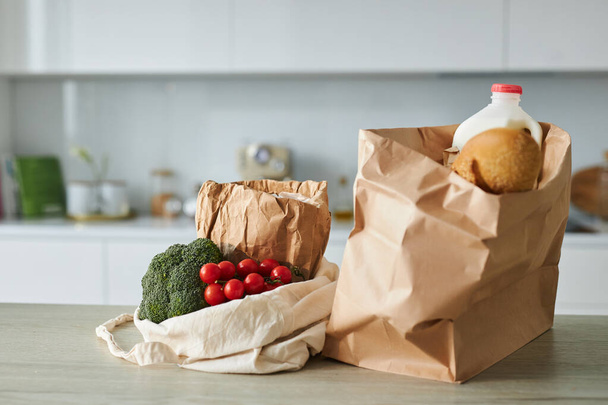 Großaufnahme von Einkaufstaschen mit frischem Gemüse auf dem Tisch in der Küche zum Kochen von Mahlzeiten - Foto, Bild