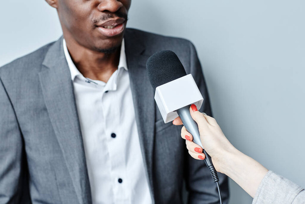 Tiro cortado de empresário preto bem sucedido falando com microfone enquanto dá interivew - Foto, Imagem