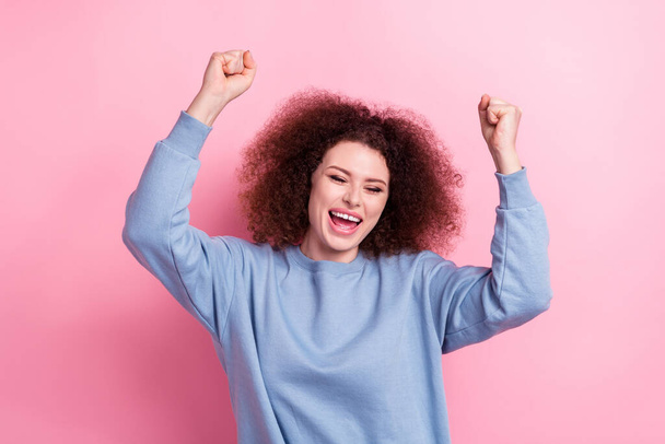 Photo of young overjoyed shopaholic girl wear blue sweatshirt fists up new collection cheap clothes offer isolated on pink color background. - Foto, immagini