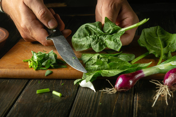 Кухар готує салат зі шпинатом та овочами на кухонному столі. Концепція приготування овочевого салату для ресторану або кафе своїми руками шеф-кухаря
. - Фото, зображення