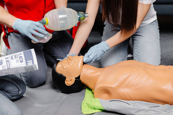 Жінка тримає дихальну сумку Ambu bag.Demonstrating CPR Cardiopulmonary rescitation training medical procedure on CPR doll at class.Paramedic демонструє практику першої допомоги для порятунку життя
. - Фото, зображення