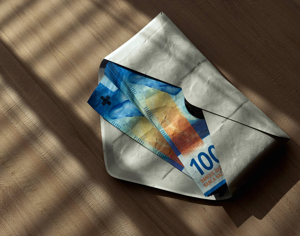 A spreading pile of franc banknotes in an envelope on a wooden surface under moody lighting - 3D render - Φωτογραφία, εικόνα