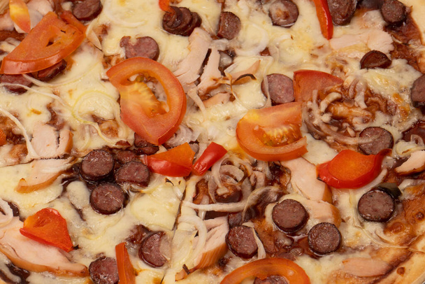 Νόστιμη πίτσα με σαλάμι, λουκάνικα, τυρί, κρεμμύδια και σάλτσα. Απομονωμένα σε λευκό φόντο. - Φωτογραφία, εικόνα