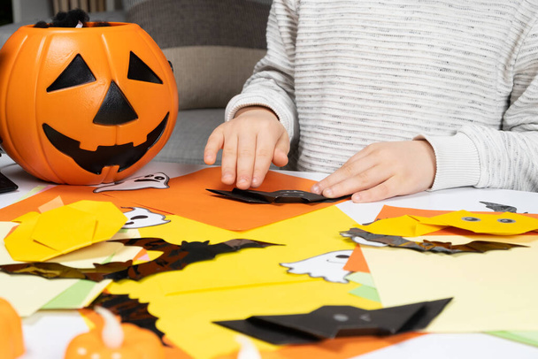 Дошкольный ребенок создает Хэллоуин оригами бумажные ремесла летучей мыши, крупным планом руки. - Фото, изображение