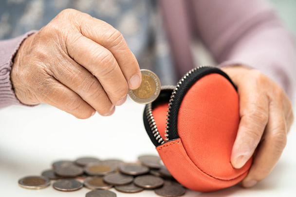 Asian senior woman holding counting coin money in purse. Poverty, saving problem in retirement. - Fotografie, Obrázek