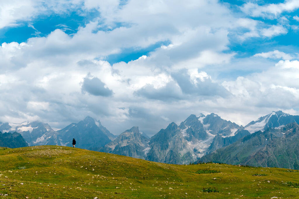Люди, туристи йдуть далеко на великій відстані, в літній сонячний день, на тлі засніжених вершин Кавказьких гір, Джорджія. - Фото, зображення