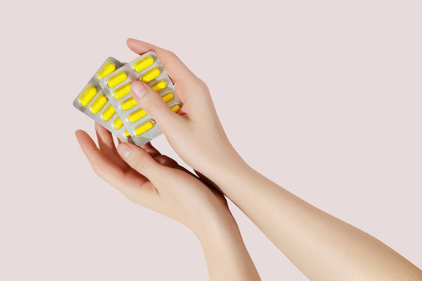 Hand holding pills in blister packs on a pink background. Health care concept. - Φωτογραφία, εικόνα