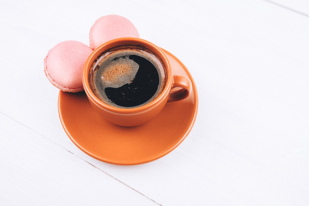 Pink macaroons with coffee on wooden background - Fotó, kép