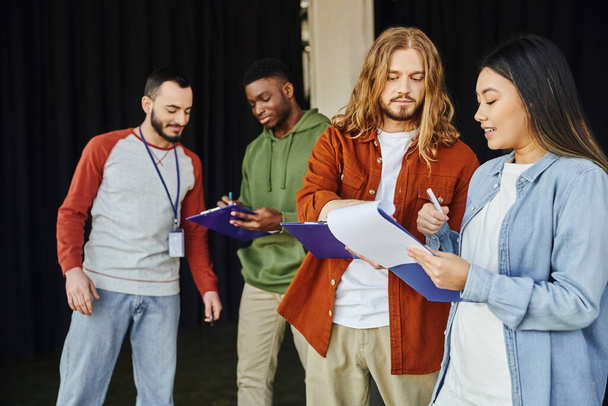 medical seminar and first aid training, young asian woman with clipboard talking to long haired man near instructor and african american participant, safety and emergency response concept - Photo, Image
