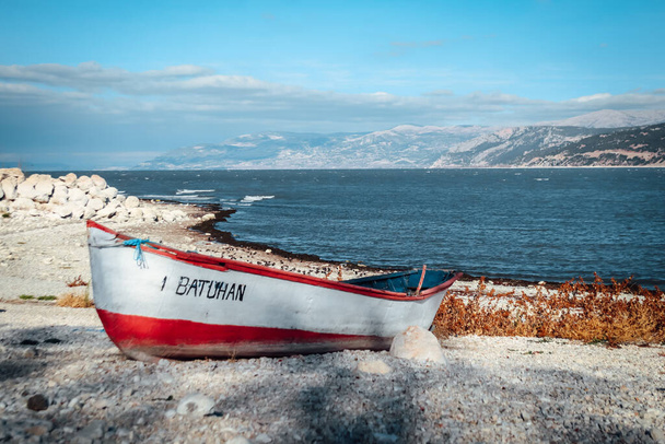 Bateau abandonné sur la rive du lac d'Egirdir avec montagnes au loin et espace de copie - Région d'Isparta, Turquie 2022 - Photo, image