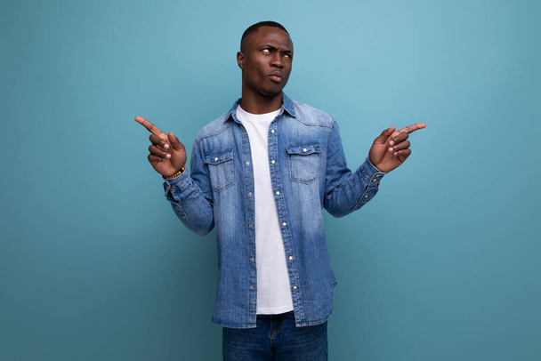 young handsome african guy in spring urban clothes pointing with his hands to the side on isolated background with copy space. - Photo, Image