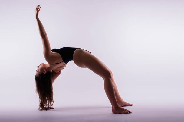Beautiful woman doing poses on a yoga class. Studio shot. - 写真・画像
