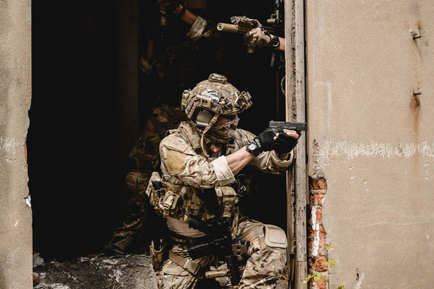 軍事作戦中に敵を攻撃する兵士の専門チーム、防護戦闘制服を着た陸軍兵士、世界大戦フィールド上のライフルを持つ兵士 - 写真・画像