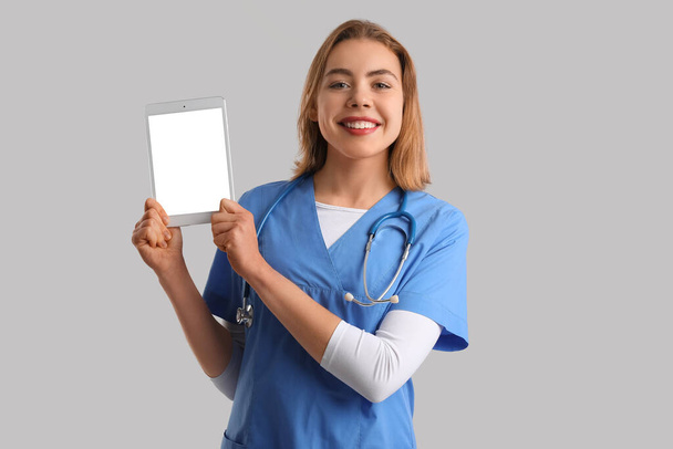 Female intern with tablet computer on grey background - Photo, Image