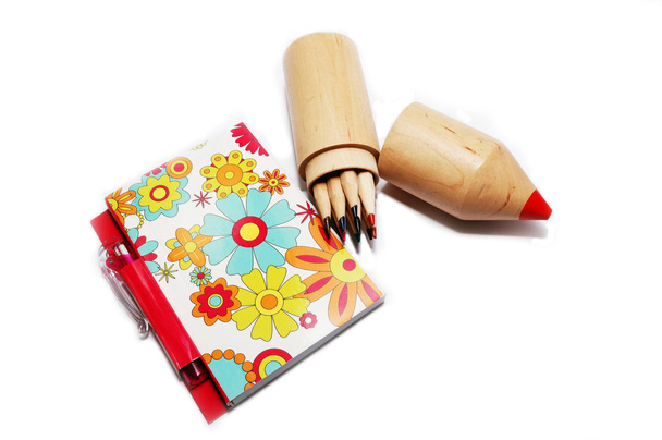 Notepad with pen and colored pencils on white background. - 写真・画像