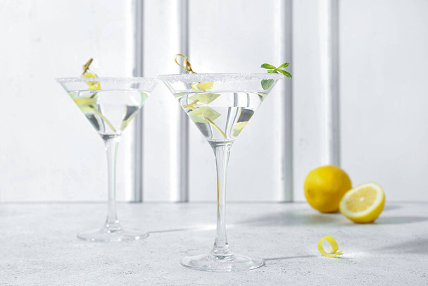 Bril lekkere martini en citroen op witte tafel - Foto, afbeelding
