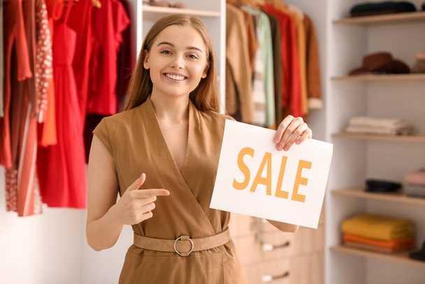 vendedor feminino apontando para venda sinal em boutique - Foto, Imagem