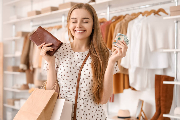 Νεαρή γυναίκα με πορτοφόλι, χρήματα και τσάντες για ψώνια σε μπουτίκ - Φωτογραφία, εικόνα