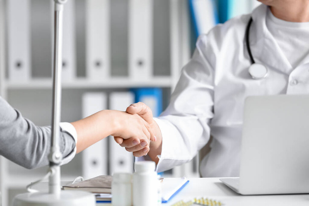 Зрілий чоловік лікар з пацієнтом потискає руки в клініці, крупним планом
 - Фото, зображення