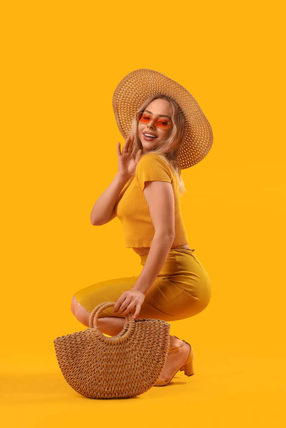 Young woman in stylish sunglasses with bag on orange background - Photo, image