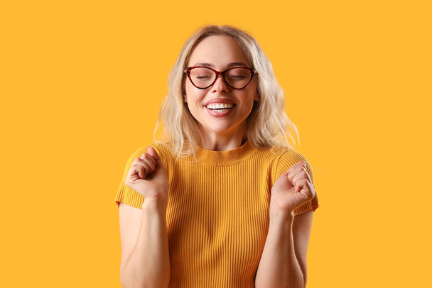 Happy young woman in stylish eyeglasses on orange background - Fotografie, Obrázek