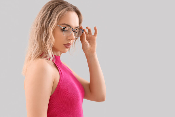 Mladá žena ve stylových brýlích na světlém pozadí, detailní záběr - Fotografie, Obrázek