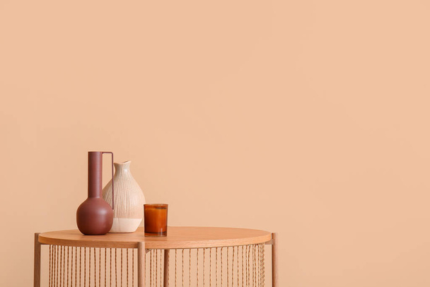 Mesa de café de madeira com vasos vazios e vela perto da parede bege - Foto, Imagem