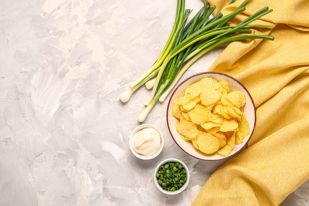 Bowls of tasty sour cream with sliced green onion and potato chips on grey background - Foto, Imagem