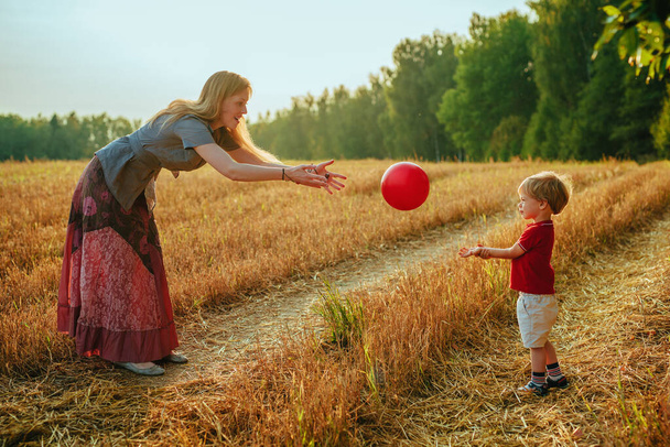 Young mother plays ball with her two-year-old son in a field - Foto, Imagem