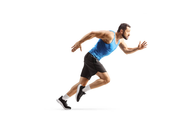 Full length profile shot of a fit male athlete running fast isolated on white background - 写真・画像