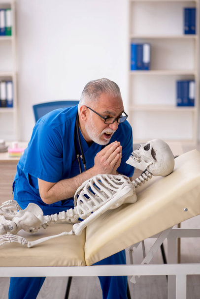 Viejo doctor examinando esqueleto en el hospital - Foto, Imagen