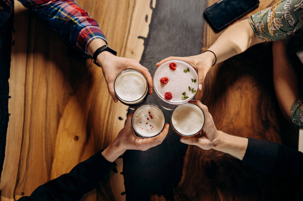 Друзі влаштовують тости і розважаються разом, п'ючи пиво і коктейлі в щасливу годину в паб-ресторані. Концепція партійного часу в стилі соціального життя
 - Фото, зображення