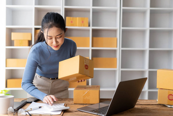 Запускаючи невеликий бізнес SME Бізнес Власник азіатських жінок підприємець працює на квитках і перевіряє онлайн замовлення на підготовку коробок для продажу клієнтам, які замовляють онлайн. - Фото, зображення