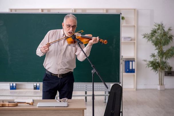 Old teacher playing violin in the classroom - Photo, Image