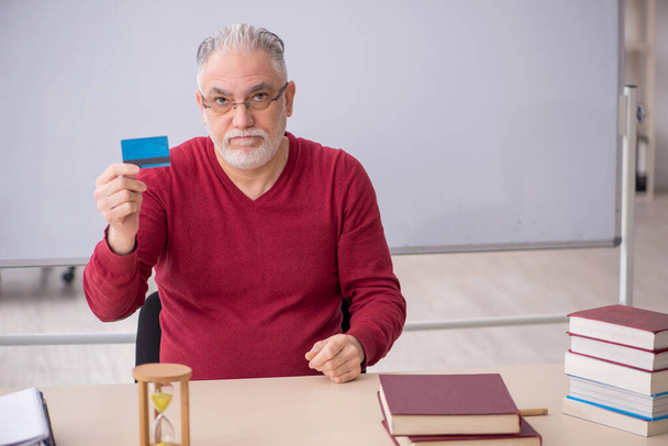 Old teacher holding credit card in the office - Zdjęcie, obraz