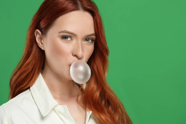 Beautiful woman blowing bubble gum on green background. Space for text - Fotoğraf, Görsel