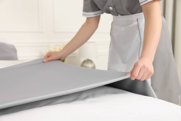 Maid making bed in hotel room, closeup - Foto, imagen
