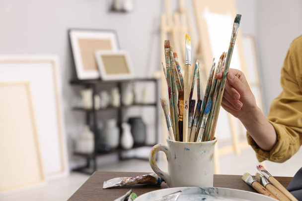 Woman taking brush from mug in studio, closeup. Space for text - Foto, Bild