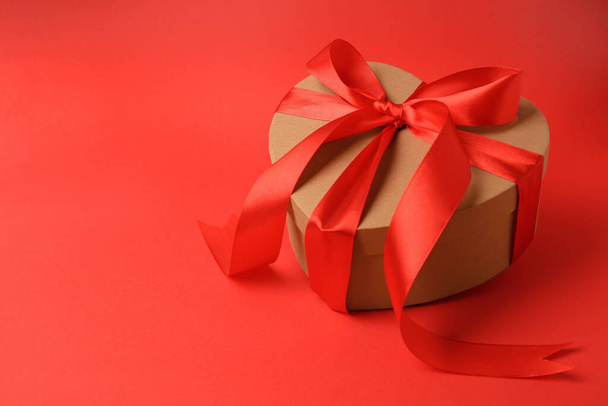 Beautiful heart shaped gift box with bow on red background, space for text - Foto, imagen