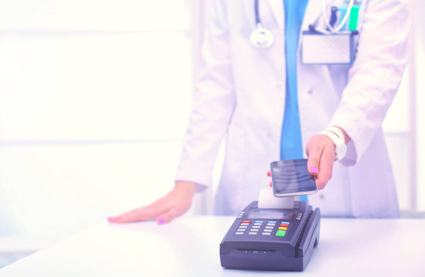 Doctor is holding payment terminal in hands. Paying for health care. Doctor. - Foto, afbeelding